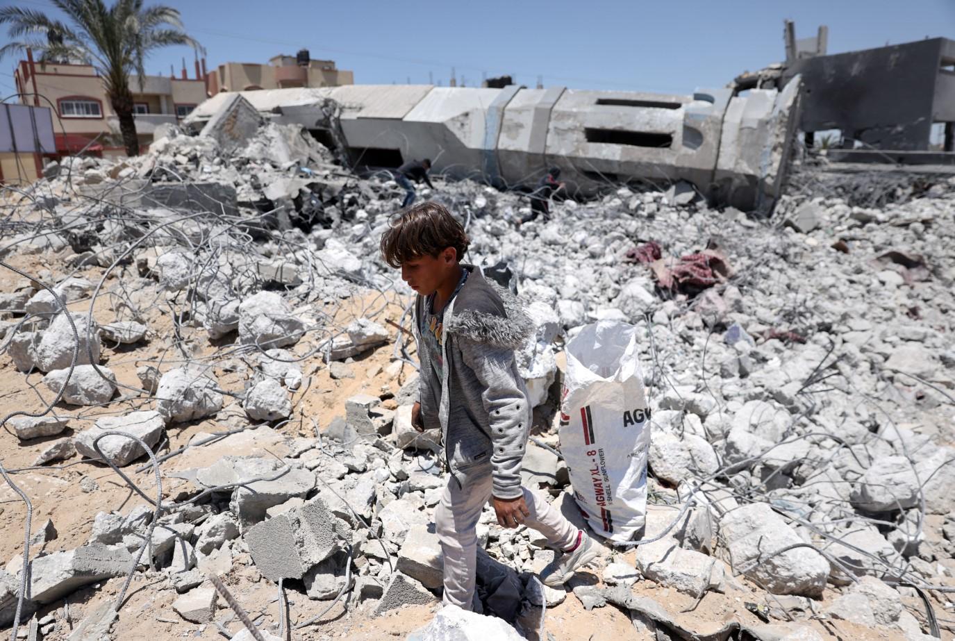 Palestinski tinejdžer sakuplja krhotine u ruševinama uništene džamije u Beit Lahiji, u sjevernom pojasu Gaze - Avaz
