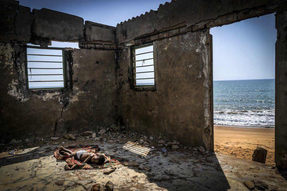 Pobjednička fotografija takmičenja na temu promjene klime i utjecaja na naš život -  pokazuje  djete koje spava u kući uništenoj erozijom obale na plaži u Gani - Avaz