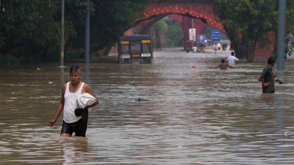 Peope wade through a flooded street in New Delhi, India - Avaz