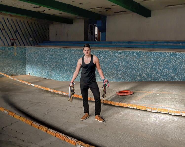 Plivač Amar Borić pored zeničkog zatvorenog bazena pokazuje medalje - Avaz