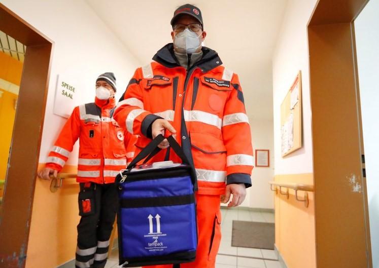 A medical worker carries a box of vials containing the Pfizer-BioNTech COVID-19, coronavirus vaccine during an inoculation program at a care home in Grossraeschen, eastern Germany , on December 27, 2020. - Avaz