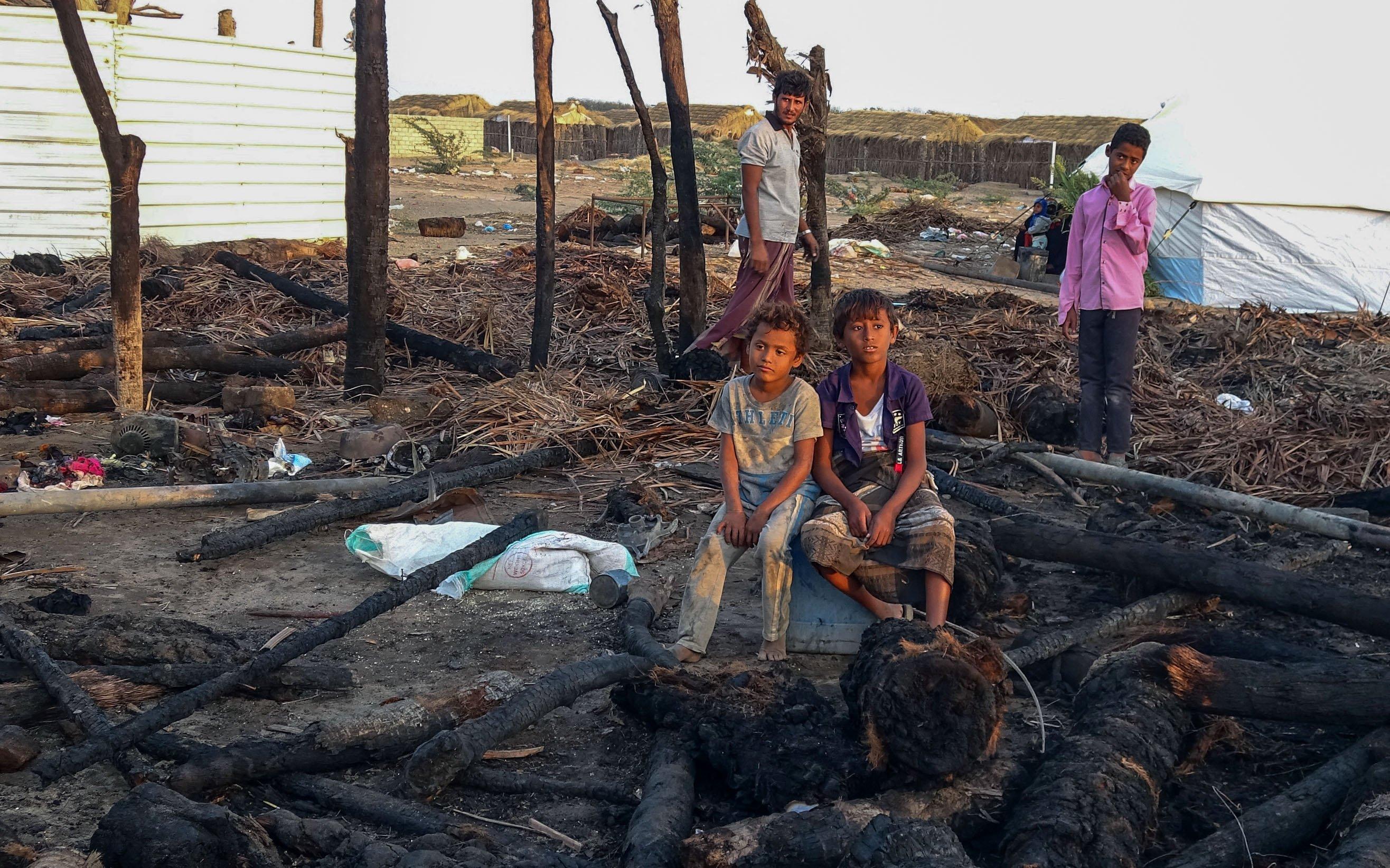 Displaced Yemen youths sit by a calcined wooden pols after a fire broke out - Avaz
