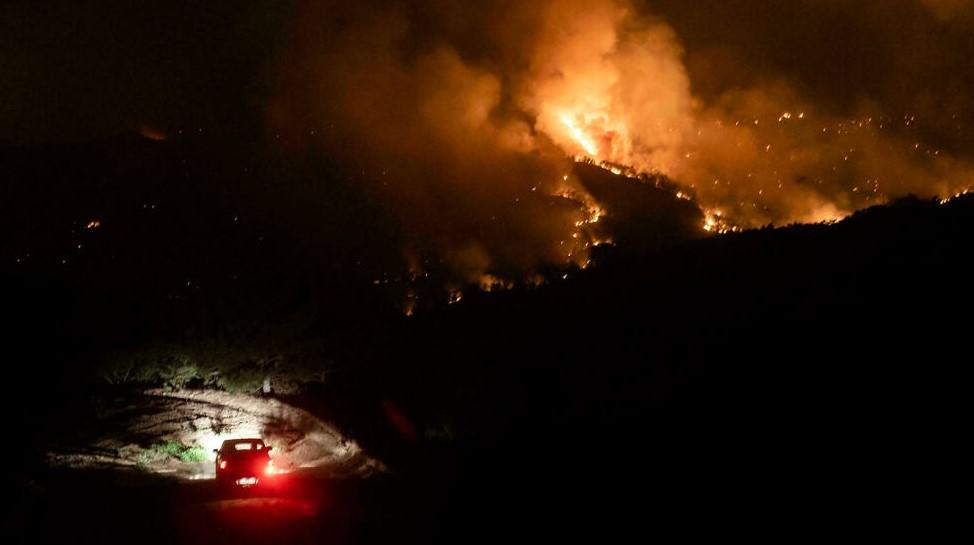 A car drives on a road in the village of Vavatsinia in the Larnaca district of Cyprus as a giant wildfire rages on the hills above during the night of July 3 - Avaz