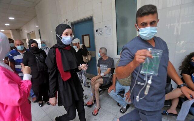 A medic assists a patient as others wait in a hallway at the Rafic Hariri University Hospital (RHUH) in Lebanon's capital Beirut on July 23, 2021. - Avaz