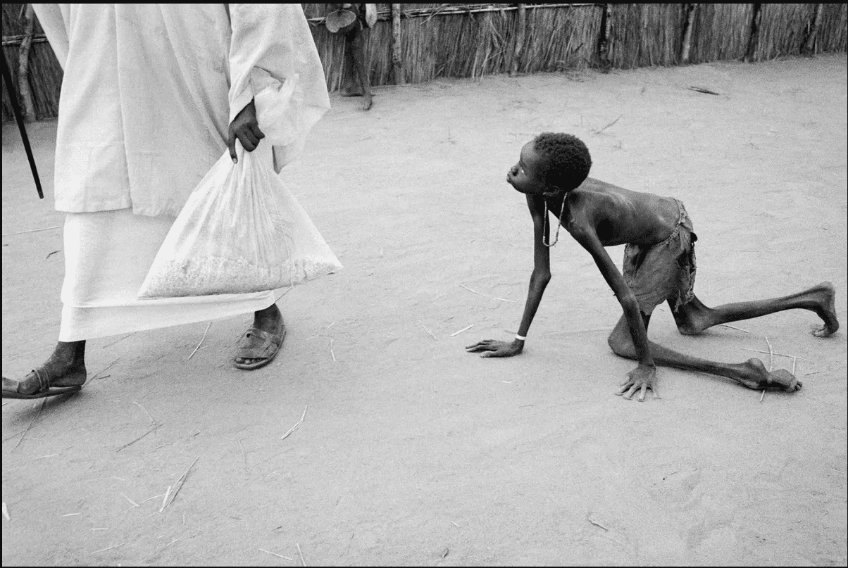 Sudan, 1998.: Dobro uhranjen muškarac krade kukuruz od izgladnjelog djeteta u centru za hranu Ljekari bez granica u Ajiepu. Glad je pogodila milione u Sudanu kasnih 1990-ih, pogoršana kršenjem ljudskih prava u sukobu između vladinih trupa i pobunjenika na jugu - Avaz