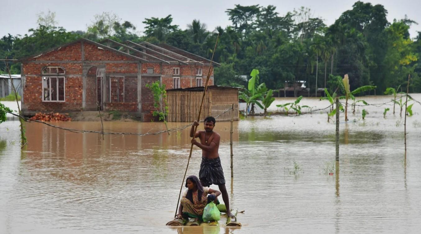 Seljani prolaze splavom pored domova u poplavljenom području nakon obilnih kiša u okrugu Nagaon - Avaz