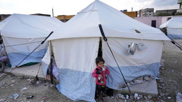 A girl whose family lost their home in the devastating earthquake stands outside a tent at a shelter camp in Killi - Avaz