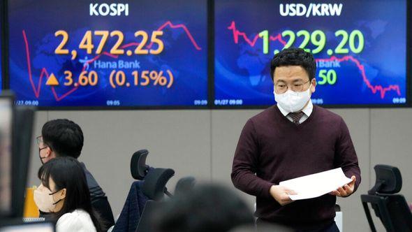 A currency trader passes by the screens showing the Korea Composite Stock Price Index (KOSPI), left, and the foreign exchange rate between U.S. dollar and South Korean won at the foreign exchange dealing room of the KEB Hana Bank headquarters in Seoul - Avaz