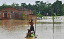 Seljani prolaze splavom pored domova u poplavljenom području nakon obilnih kiša u okrugu Nagaon