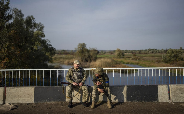 Ukrajinski vojnici sjede na porušenom mostu preko reke Oskil u nedavno oslobođenom gradu Kupijansk